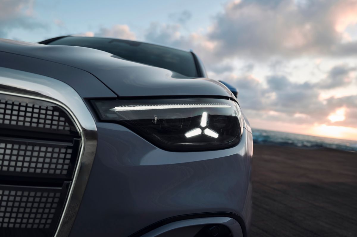 Nahaufnahme des leuchtenden Sternlogos im Scheinwerfer eines grauen Mercedes-Benz GLC bei Dämmerung