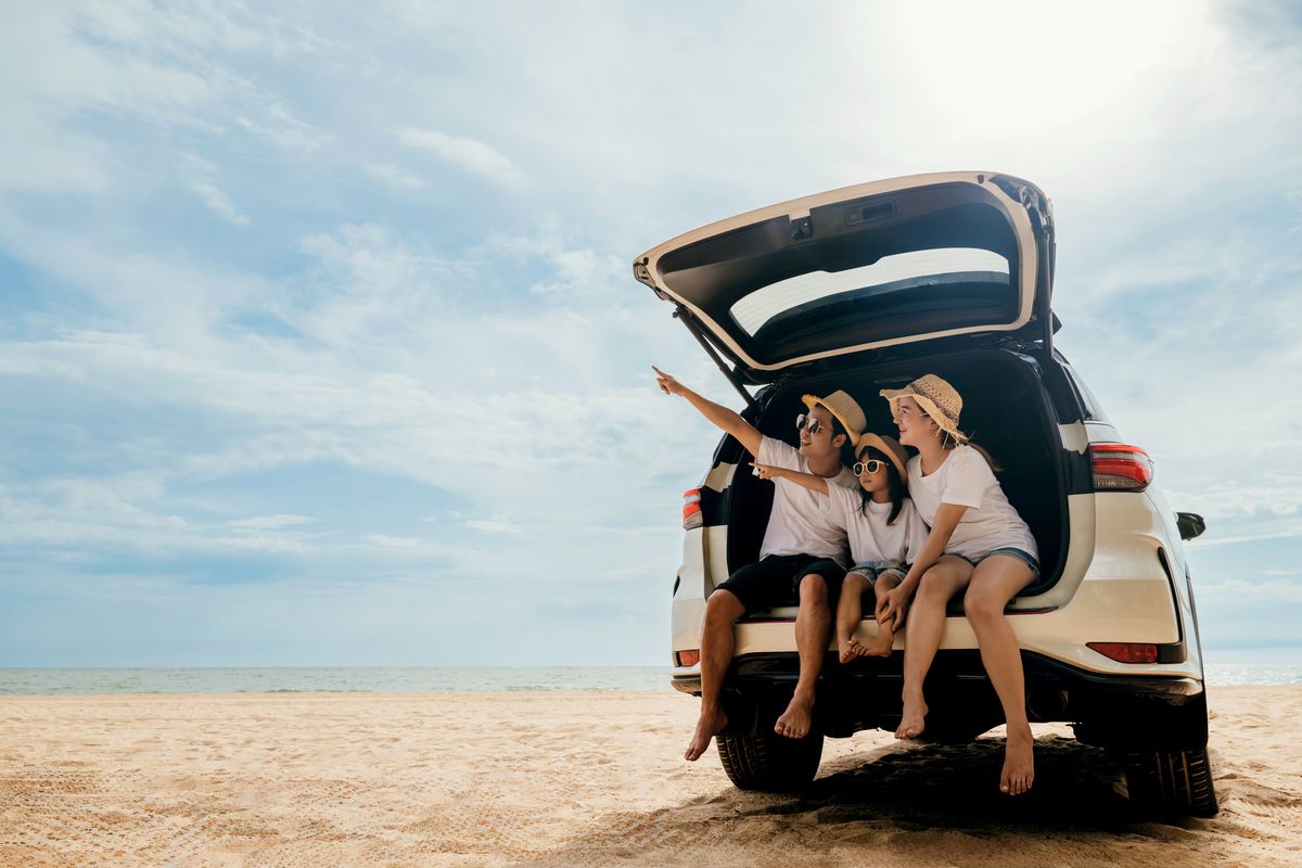 Ein Auto parkt am Strand und eine Familie sitzt im Fahrzeug