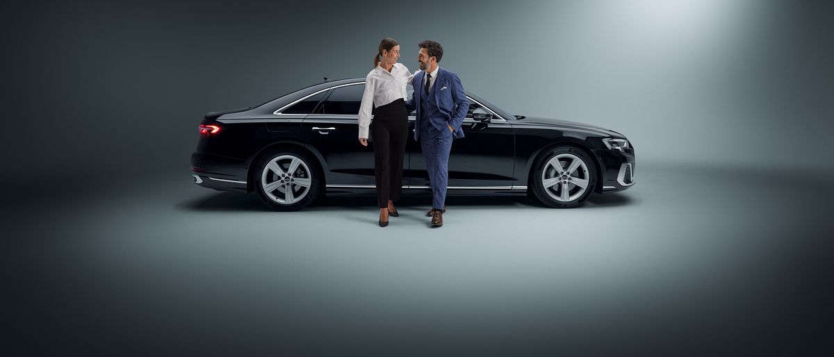 Un hombre y una mujer delante de un coche AUDI Business