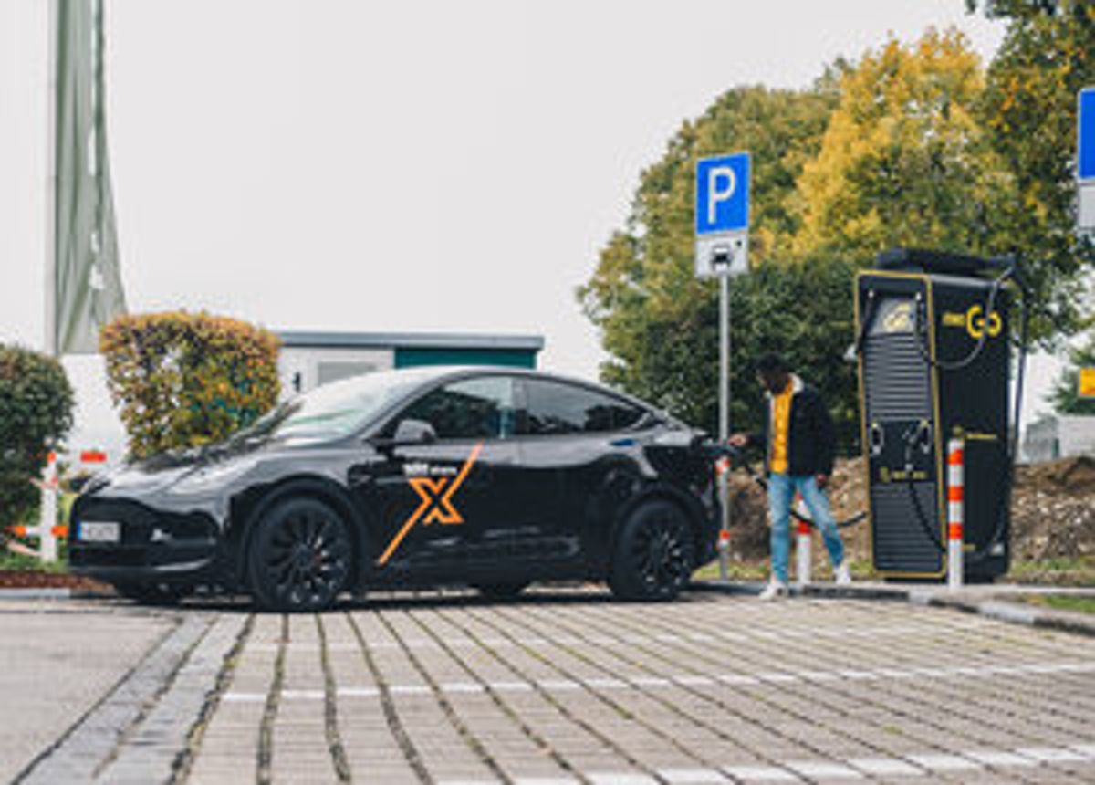 Seitenansicht eines Tesla Model Y Performance in der Farbe Solid Black vor einer Ladestation