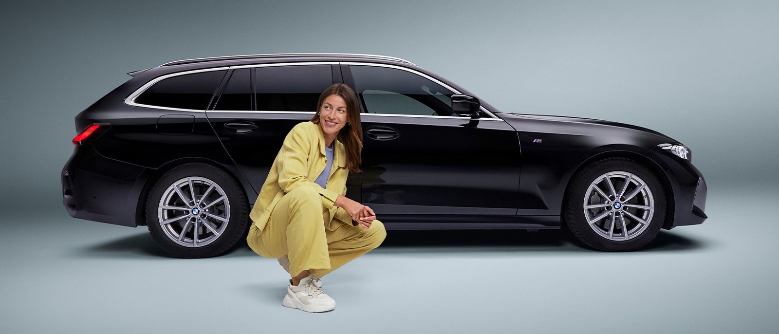 Eine Geschäftsfrau mit Anzug sitzt vor einem Audi Kombi