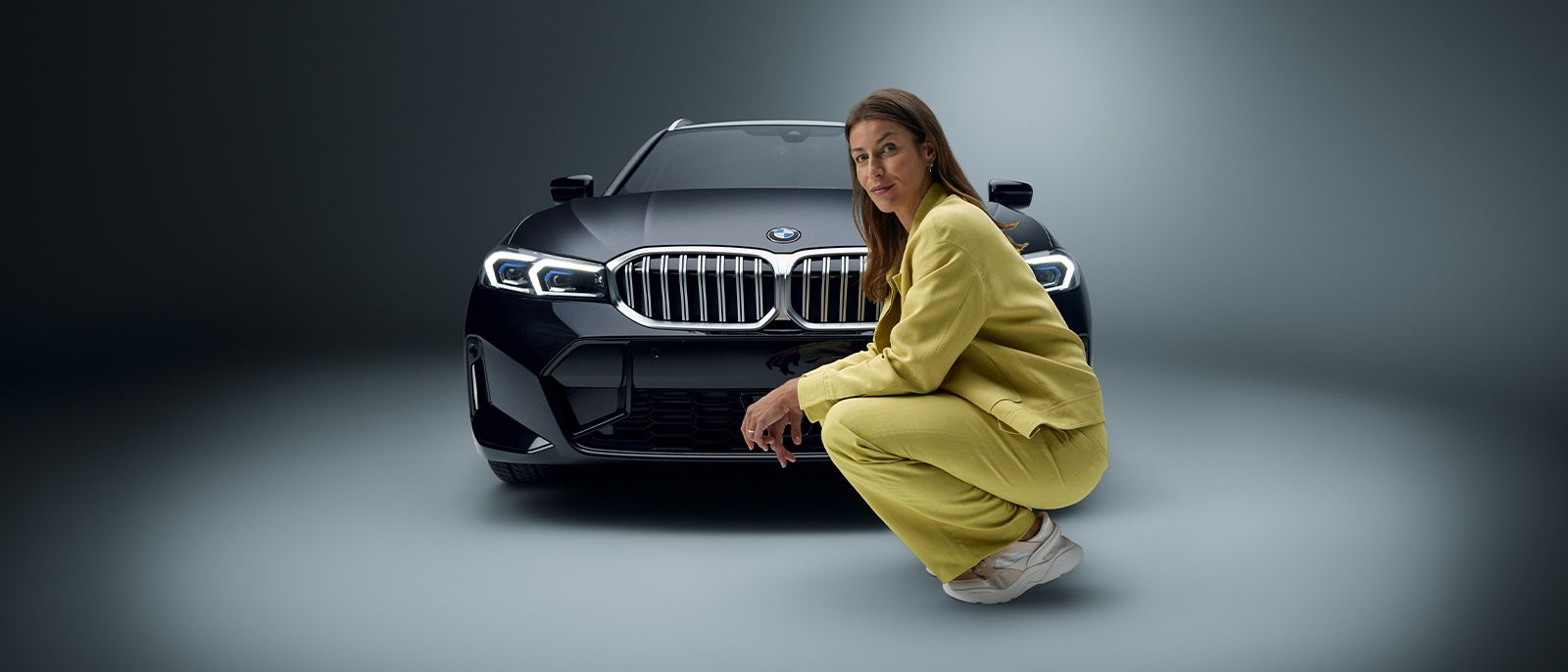 Woman kneeling in front of BMW