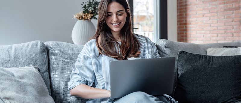 a women working on her laptop on a sofa