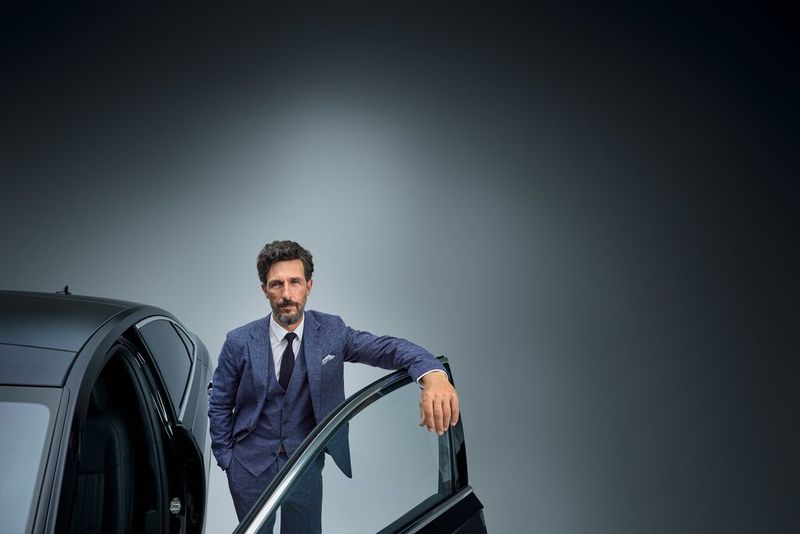 A businessman is leaning on a rental car