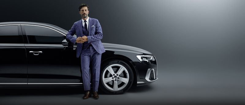 a business man standing in front of his car