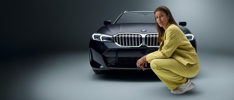Businessfrau kniet vor einem Firmenwagen